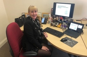 Gill Bragg sits at desk