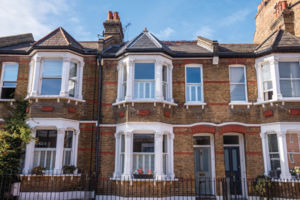 Traditional British brick terraced houses with a metal front fence on a sunny autumn day. Greenwich, London, UK