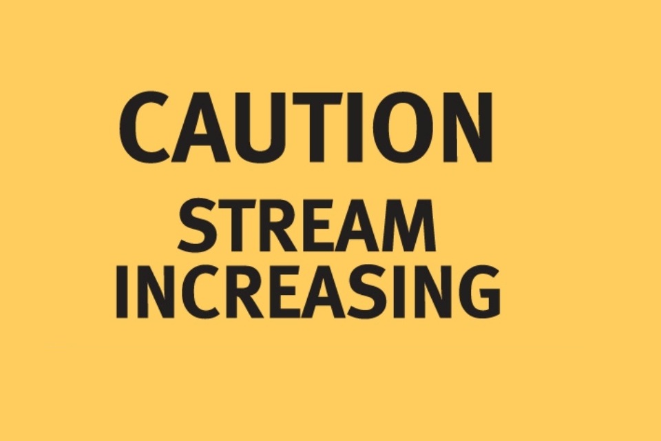 A yellow sign with black text reading 'Caution: Stream increasing'.
