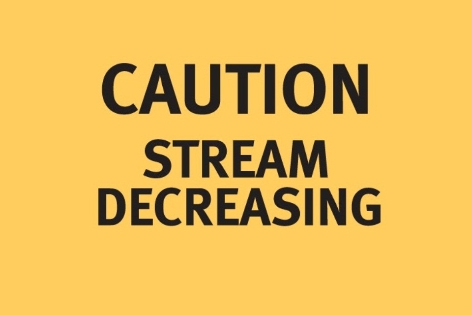 A yellow sign with black text reading 'Caution: Stream decreasing'.
