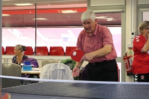 An elderly man playing table tennis