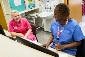 Two nurses chatting at reception desk