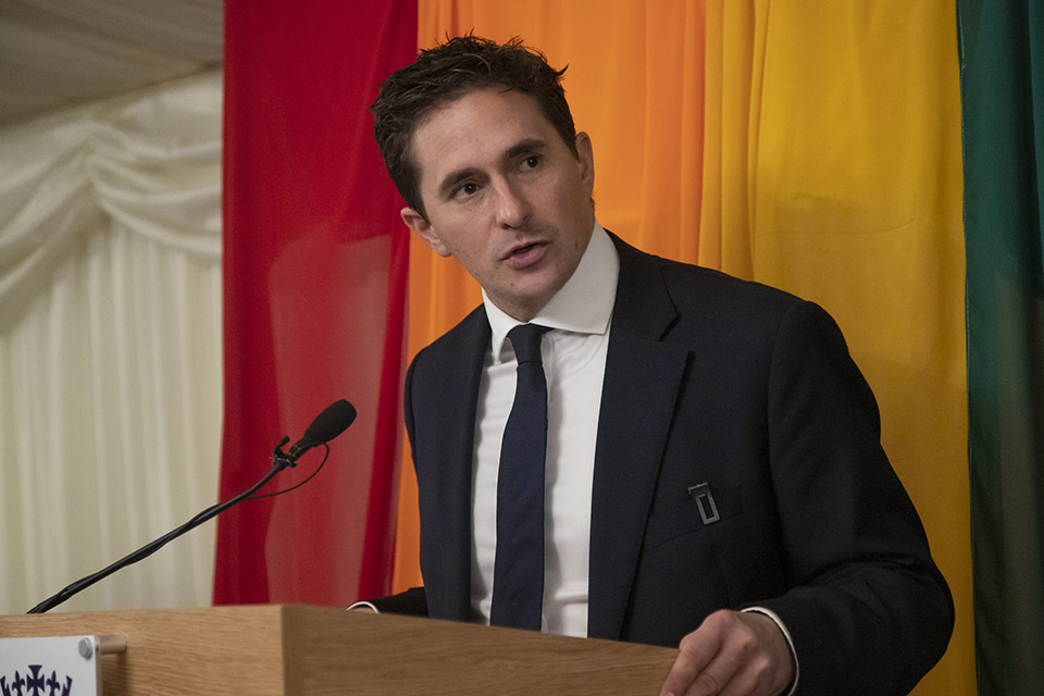 Minister for Defence People and Veterans Johnny Mercer speaking at the LGB20 reception with a rainbow flag behind him