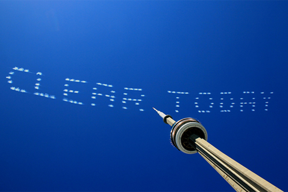 Image showing a skytyping message saying ‘Clear today’ created in white smoke puffs against a blue sky background, released in a way resembling printed letters