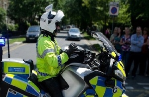 Policeman on stationary motorbike with onlookers
