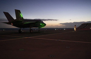 Image depicts F-35 Lightning jet on HMS Queen Elizabeth flight deck at sunset