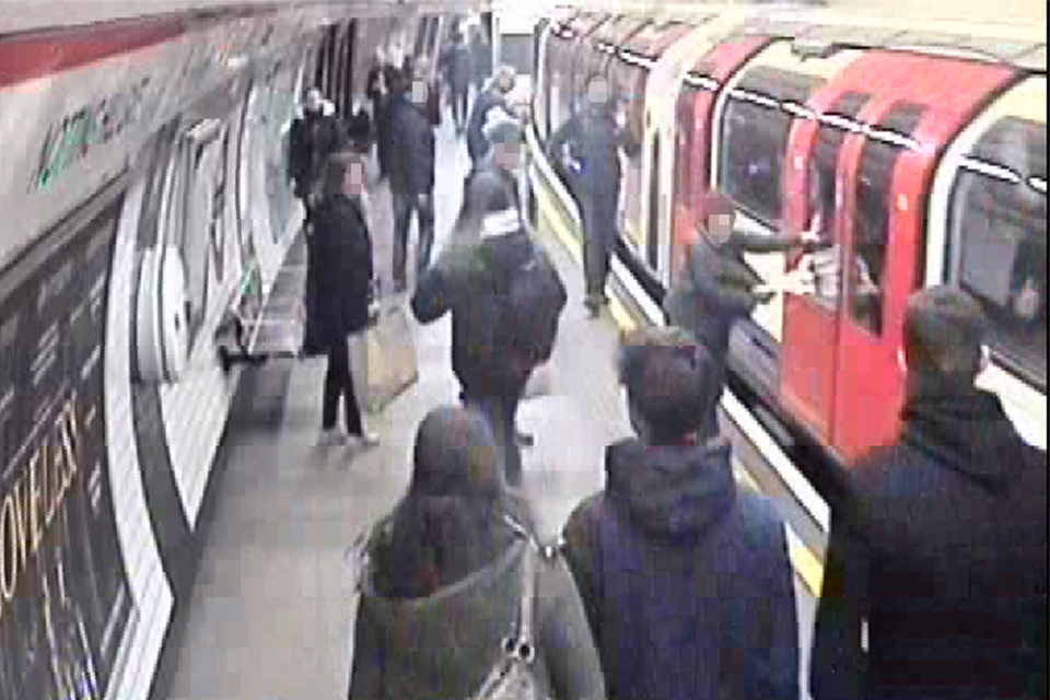 CCTV showing a passenger with bag trapped in a London Underground train doors at Notting Hill Gate station. Other passengers are on the platform.