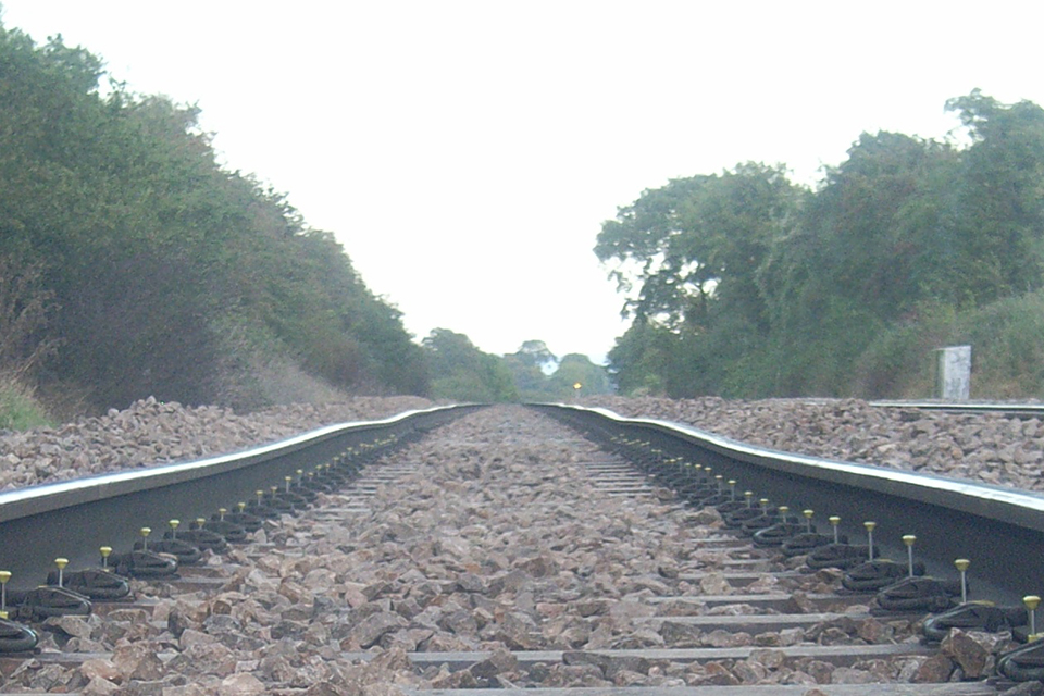 View from the four foot looking across the ballast along sleepers. The uneven rails go into the distance.