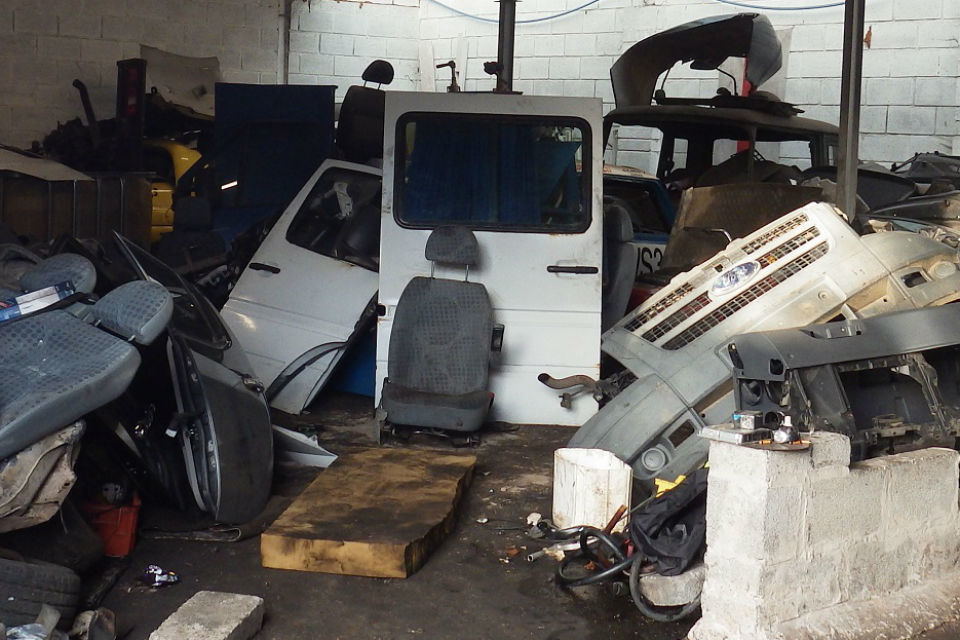 A van door, chairs and other car parts being stored inside a garage