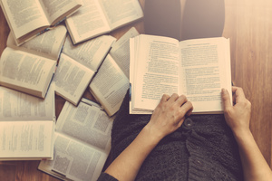 Man reading a book with books beside him