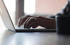 An image of hands typing at a laptop computer