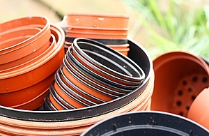 A pile of small red plastic plant pots stacked into a larger red plant pot