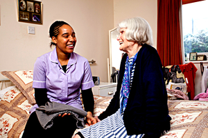 A carer chatting to an elderly woman in her room