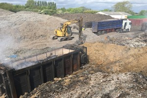 Burning waste and soil with a digger and a lorry in the background