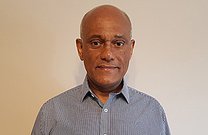 An RAIB inspectors dressed casually stands against a plain beige background