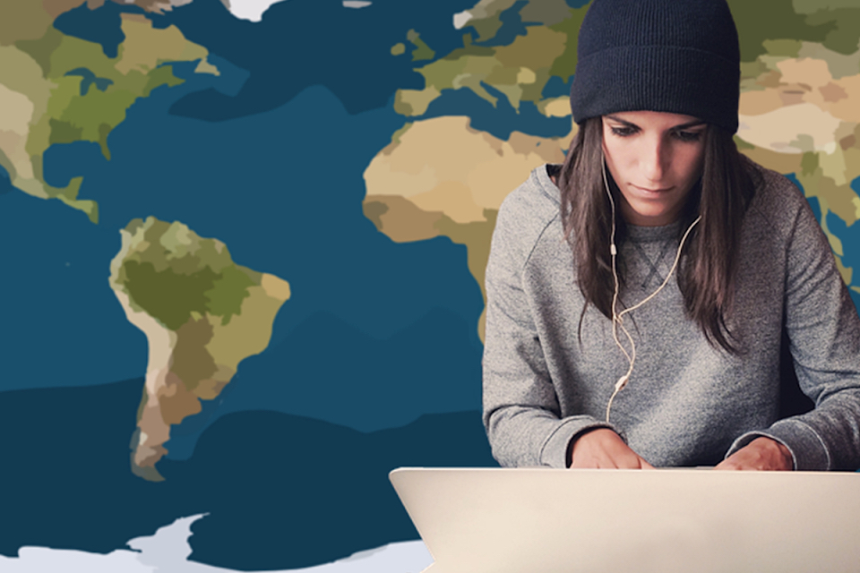 woman typing on a laptop with a map of the world behind her