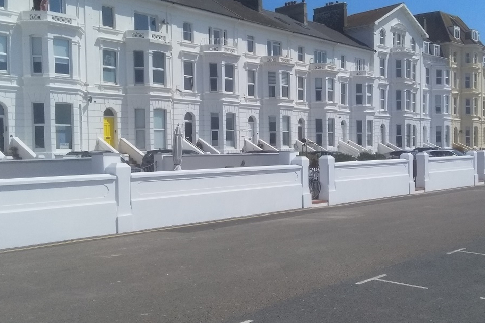 A white wall in front of properties on the seafront in Exmouth