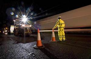 An image of people working on a motorway at night