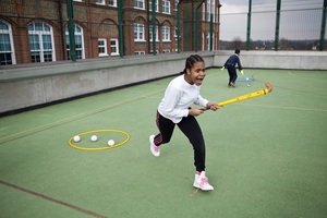 A girl playing hockey in a school playground