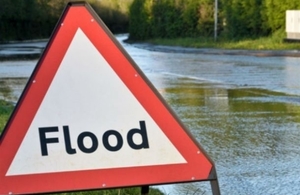 flood sign in front of a flooded road