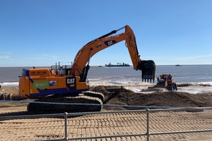Heavy equipment moves a large amount of sand on a beach