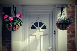 Hanging baskets either side of a white front door.