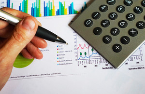 Pen in hand with graphs and charts in the background.