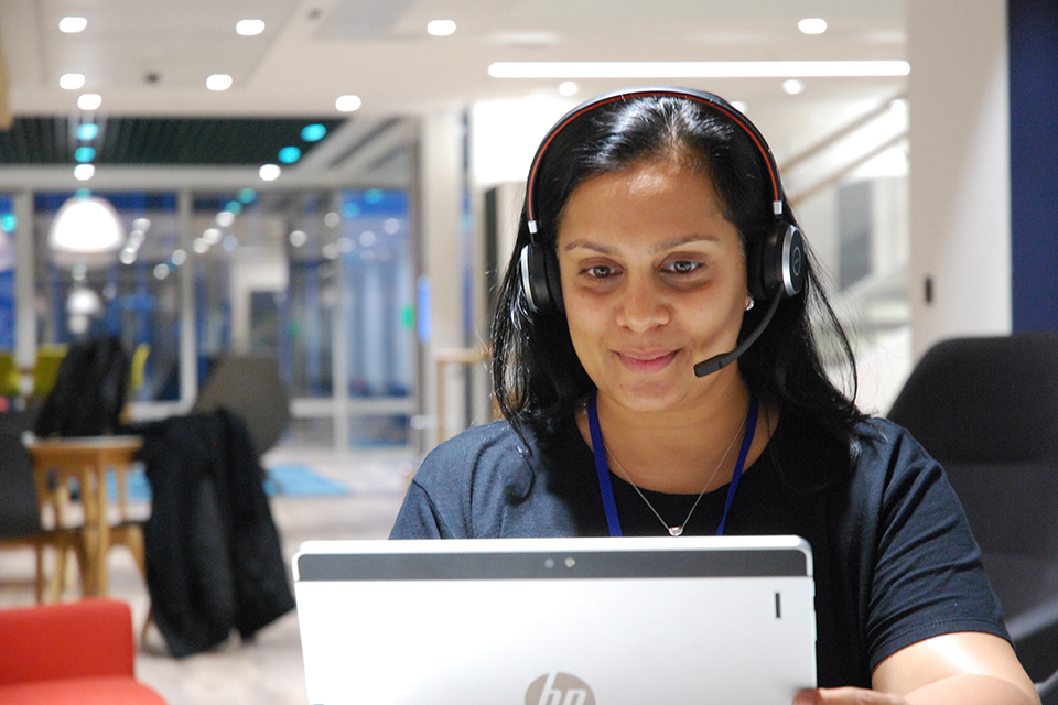 Photograph: A woman using a computer with a headset on.