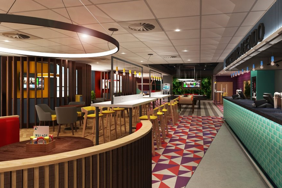 An empty wide open plan area includes a bar, seating booths and communal seating. In the background there's a football machine and widescreen TV. The carpet has a geometric pattern and the room is bright and welcoming.