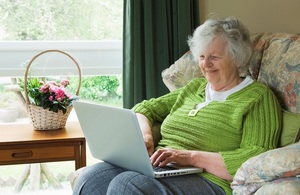 An older woman sitting in an armchair using a laptop