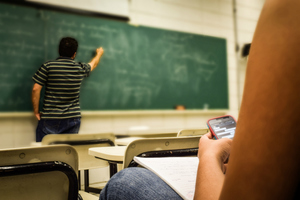 Teacher writing on blackboard in classroom