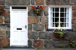 A white front door and window of a cottage in Snowdonia, North Wales.