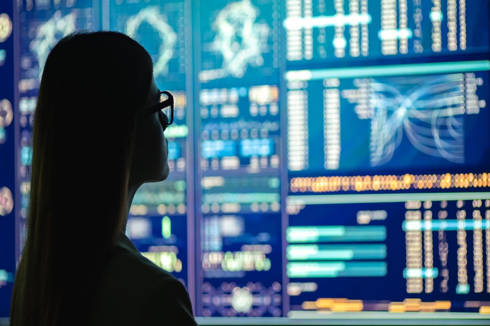Photo of a woman looking at data on screens