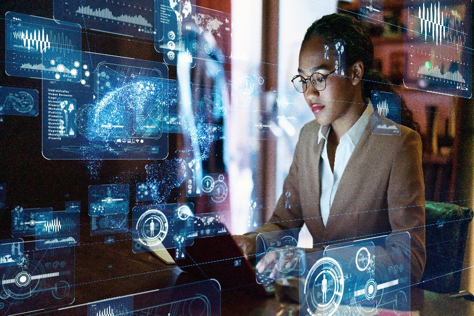 Photo of a woman at a computer with data graphics
