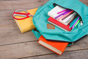 School bag on table with books and stationery 