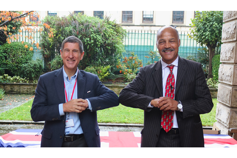 Two men smiling at the camera rubbing elbows to substitute for a handshake during the Coronavirus.