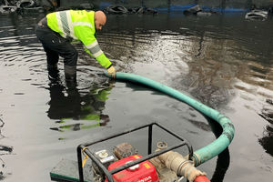 An officer from the Environment Agency uses a pump at fire site