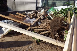 A tree stump, wooden fencing and garden waste in the back of a flatbed lorry
