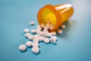 Medication bottle with white pills on blue background 
