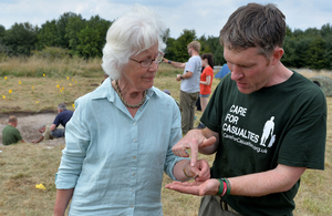 Richard Osgood and Rosemary Baillon stand next to each other. They look closely at an artefact in Rosemary's hand.