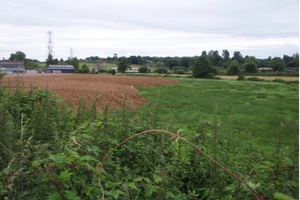 Image of tonnes of brown soil encroaching onto field of green grass