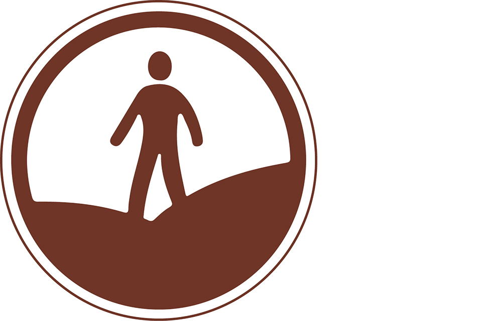 Round brown symbol with a person walking over hills