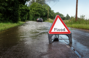 flood sign in front of a flooded road and car