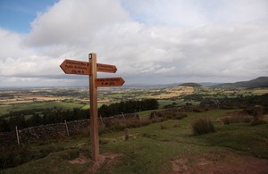 image of a wooden post against a pathway and green fields.