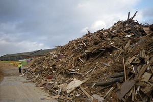 A huge of pile of wood waste, with an Environment Agency officer in attendance