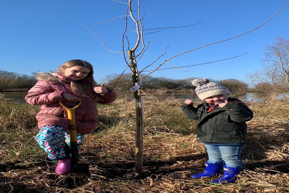 Two children standing by one of the trees.