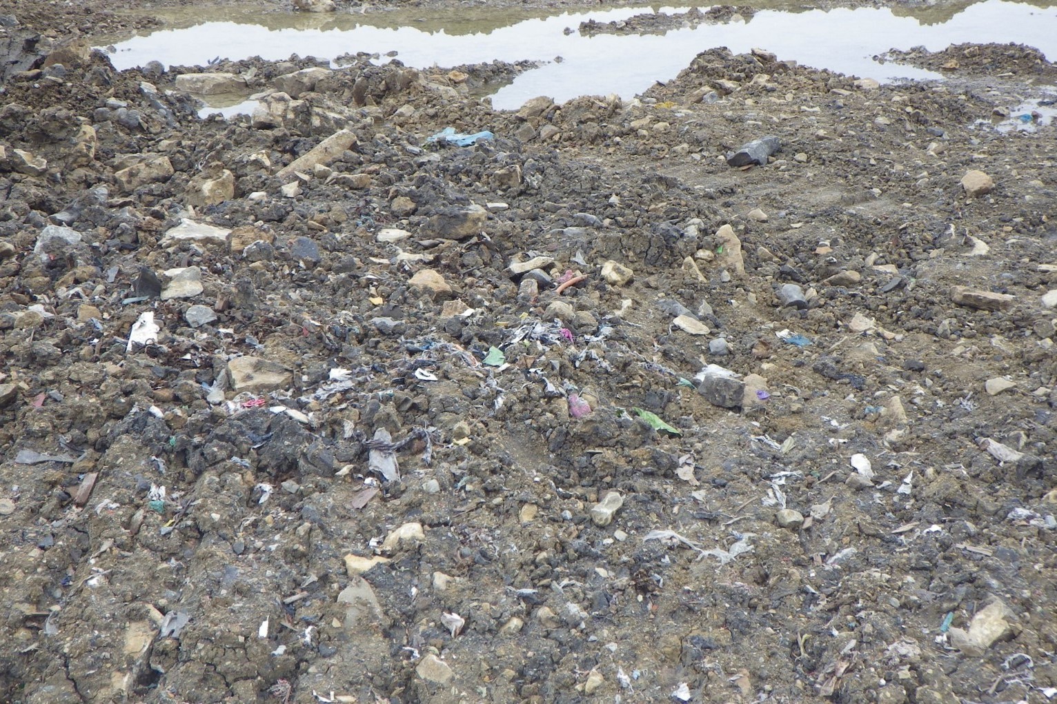 Close up picture of the ground which is littered with plastic shreds and other material