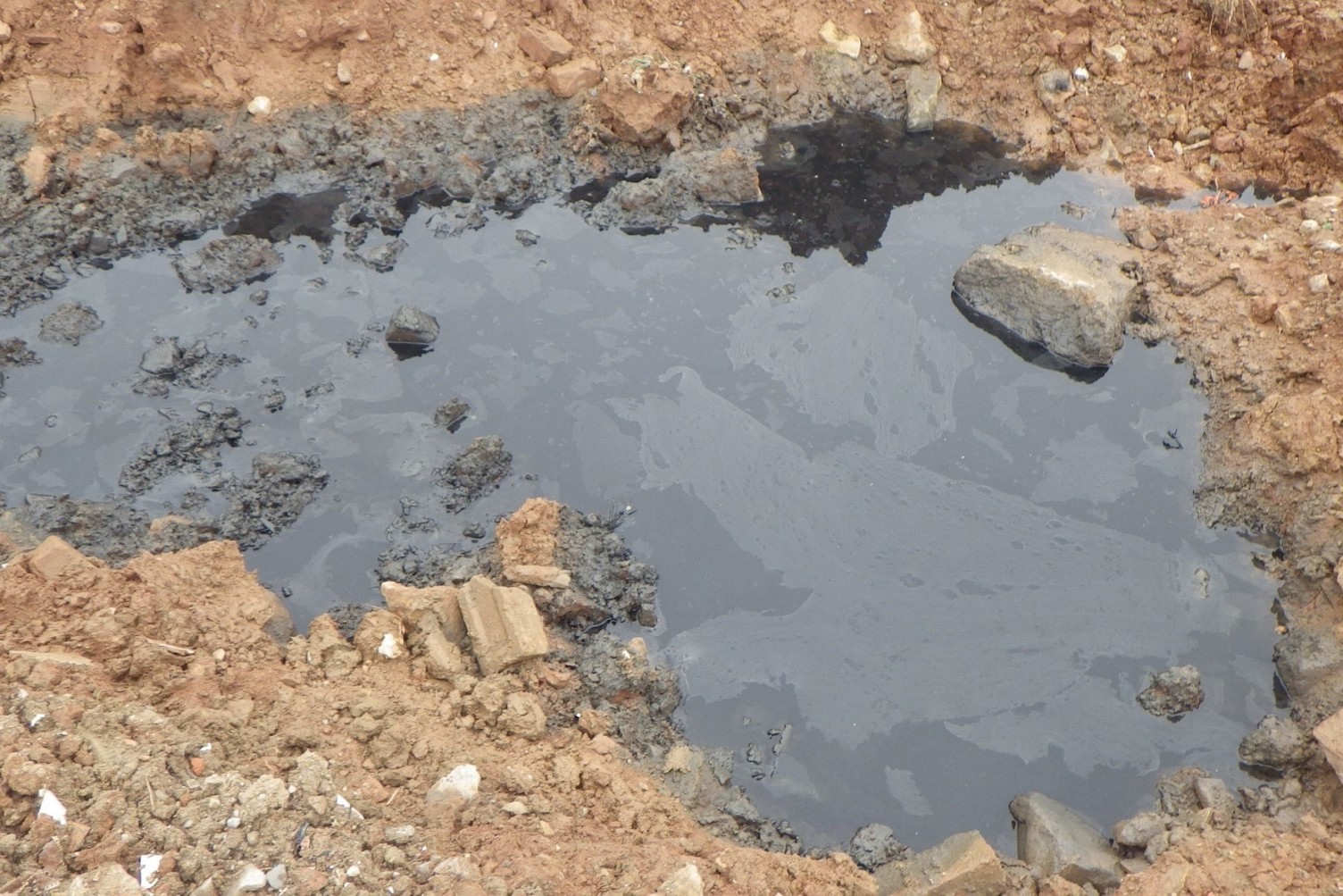 Close up picture of a greasy, black puddle on the ground