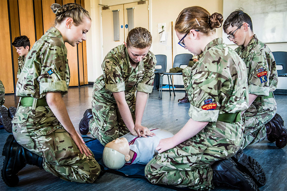 4 Cadets in uniform practise CPR on a dummy.