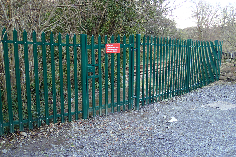 Dark green spiked gate located above railway cutting